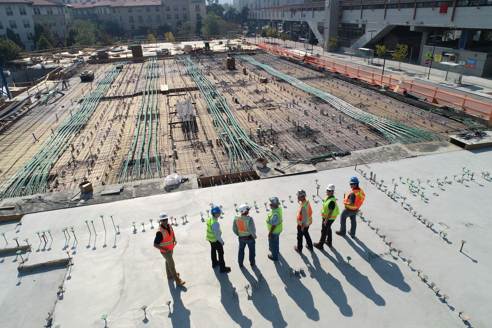 Equipe de engenharia observando uma obra a partir de uma laje, com a estrutura de armação ao fundo