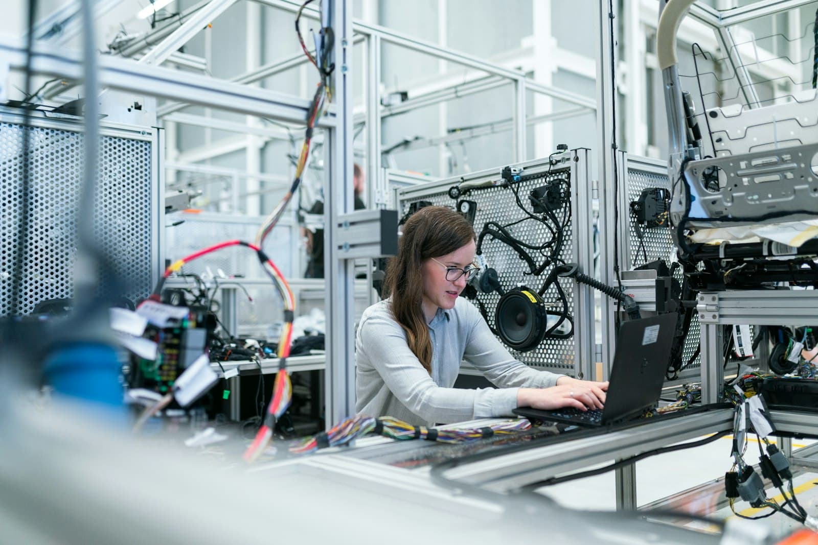 Engenheira trabalhando em um notebook em uma bancada de laboratório industrial